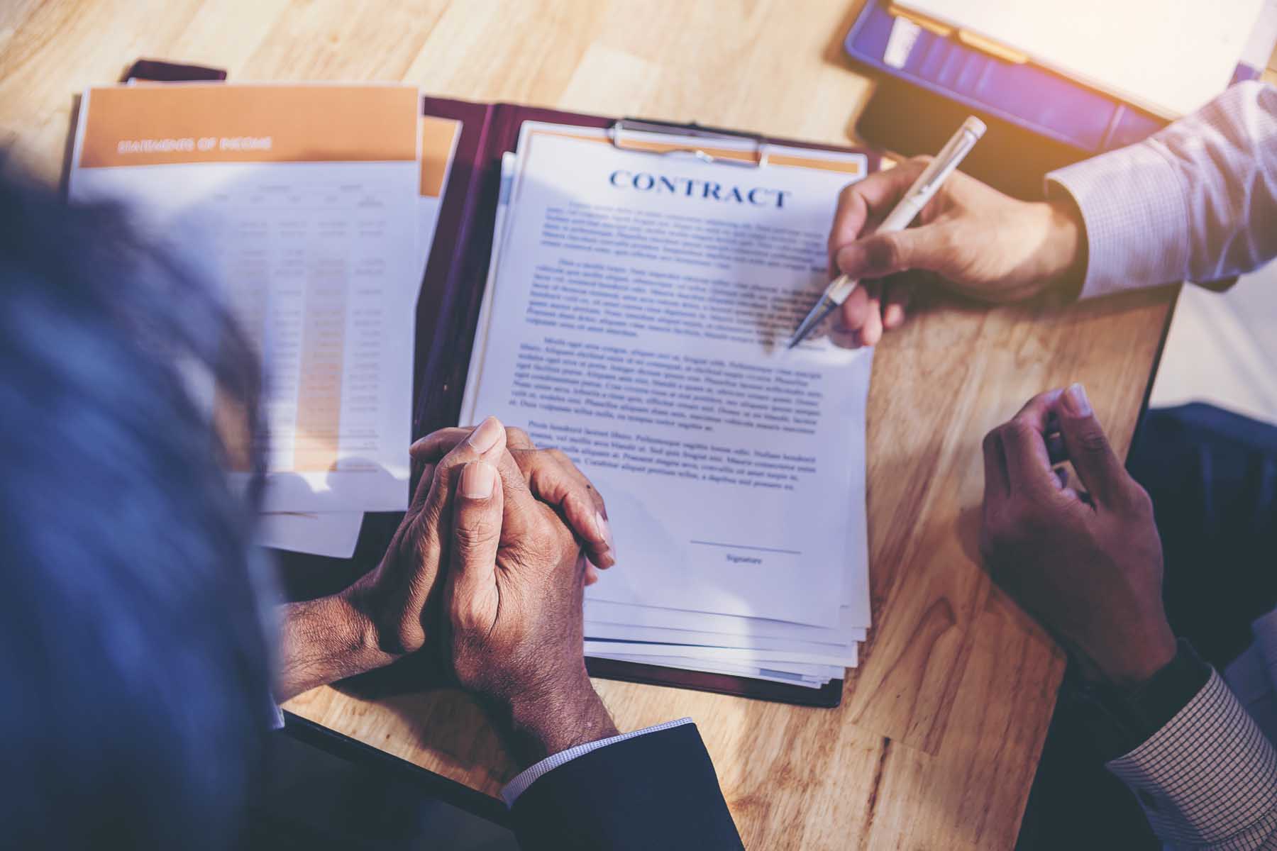 Two people reading through a contract and signing